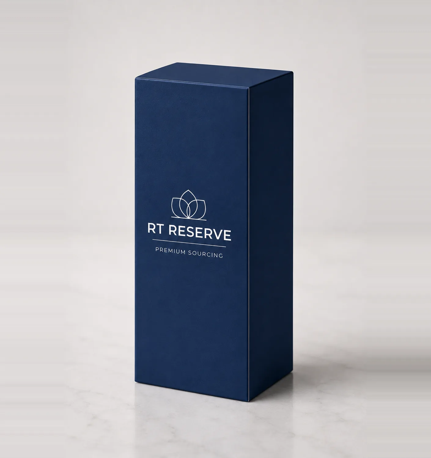 RT Reserve carton photographed on a pale marble surface: a navy reverse tuck-end box with the lotus mark, RT RESERVE wordmark and PREMIUM SOURCING printed in white